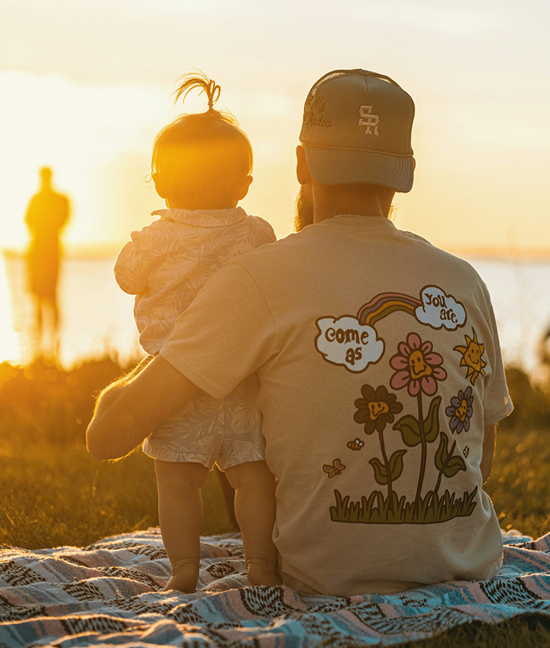 father and baby on blanket at beach